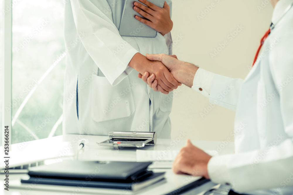 Doctor at the hospital giving handshake to another doctor showing success and teamwork of profession