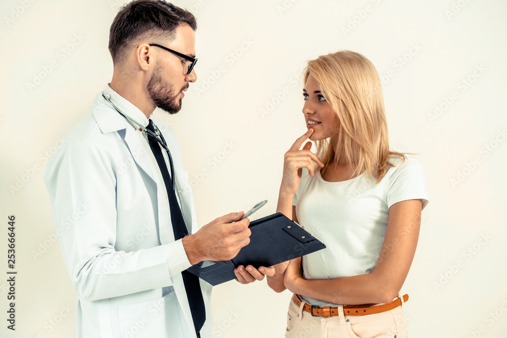 Male doctor and female patient with documents of patients health record are having conversation in h