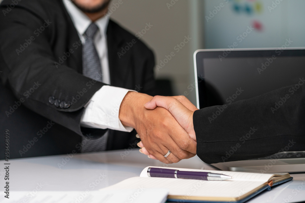 Business people agreement concept. Businessman and Asian businesswoman do handshake in the office.