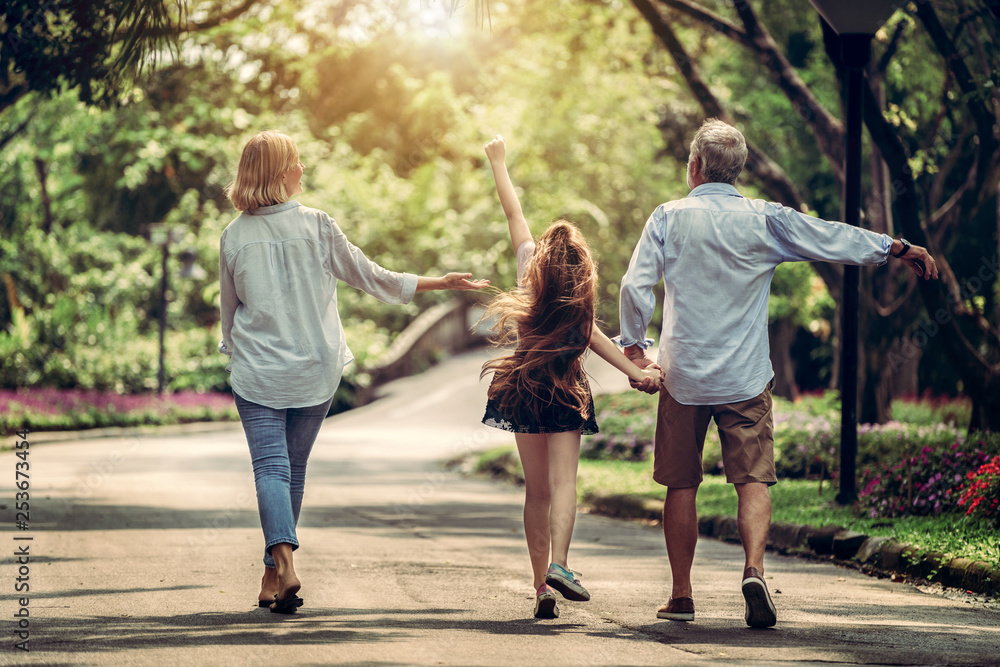 Happy healthy family walk together on path in the park in summer. Concept of family bonding.