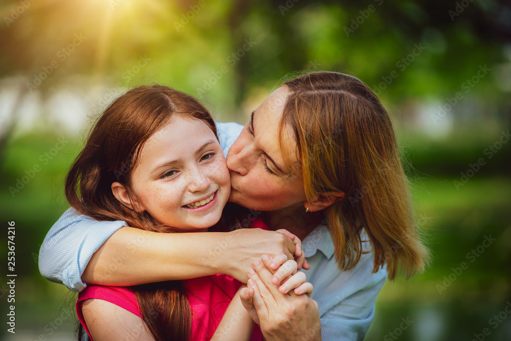 户外公共公园里放松快乐的母亲和年幼的女儿。亲子关系和儿童概念。