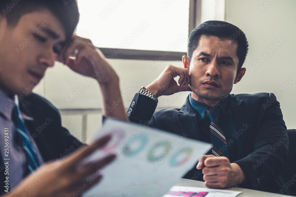 Unhappy business manager and young businessman partner in meeting room at the office. They are under