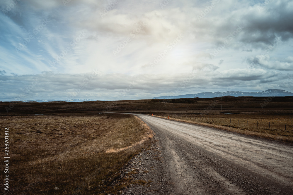 Empty gravel dirt road through countryside landscape and grass field. Nature off road travel trip fo