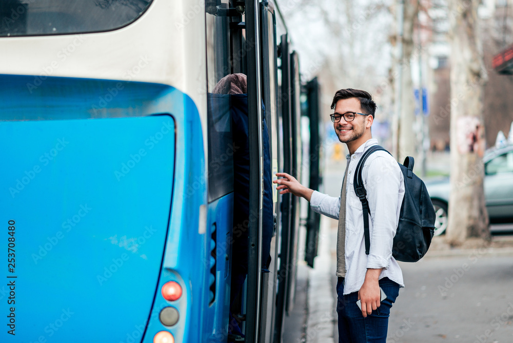 Handsome smiling young man getting into bus.