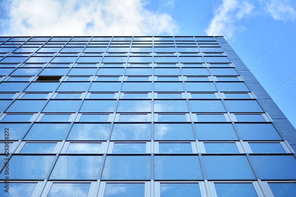 Surface of glass building with the reflection of clouds