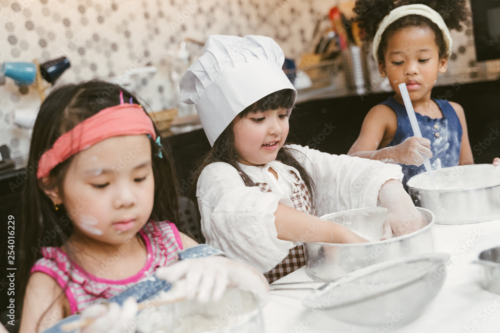 Group of kids are preparing the bakery in the kitchen .Children learning to cooking cookies