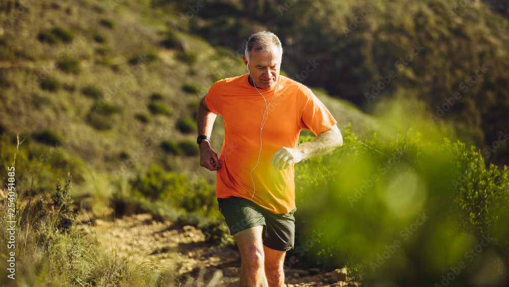 Senior athletic person trail running on a hill