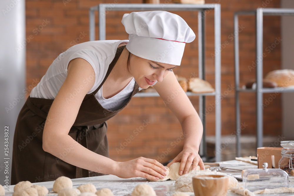 Female baker cooking buns in kitchen