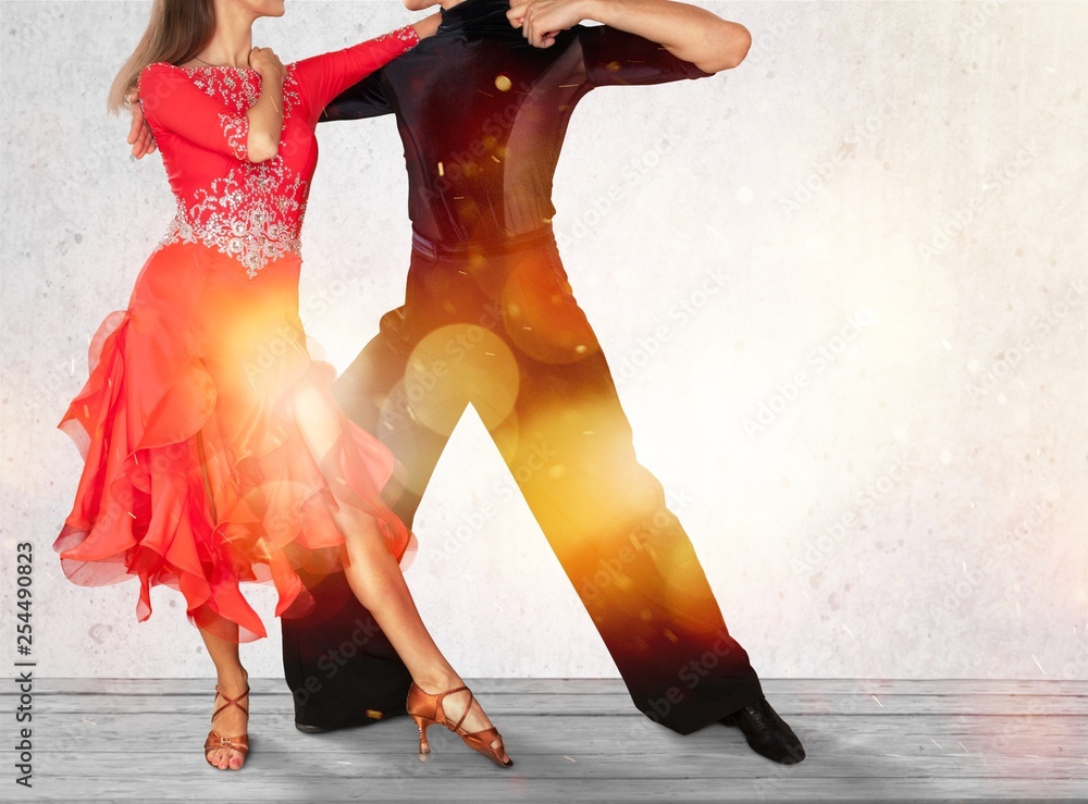 Man and a woman dancing Salsa on grey wall background