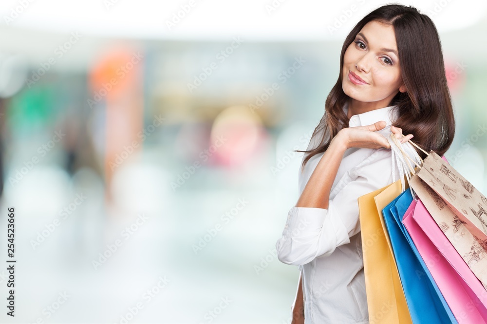 Young woman with shopping bags on blurred shopping mall background