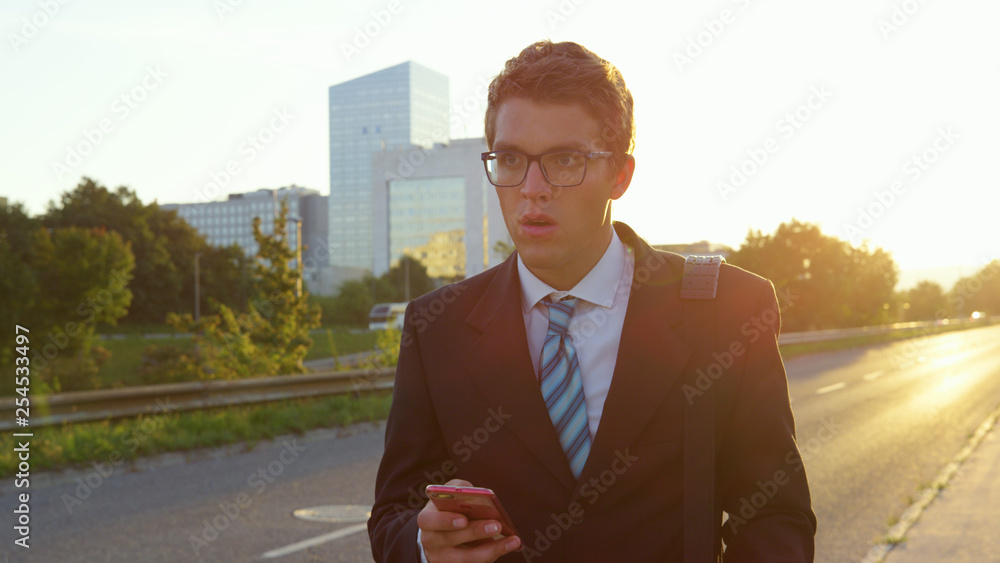 SUN FLARE: Stressed yuppie looks around the city as he walks home at sunset.