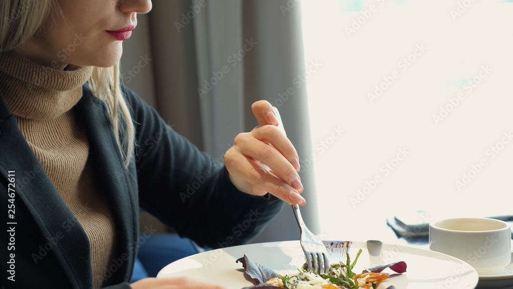 Close up unrecognizable woman eating salad sitting in cafe.