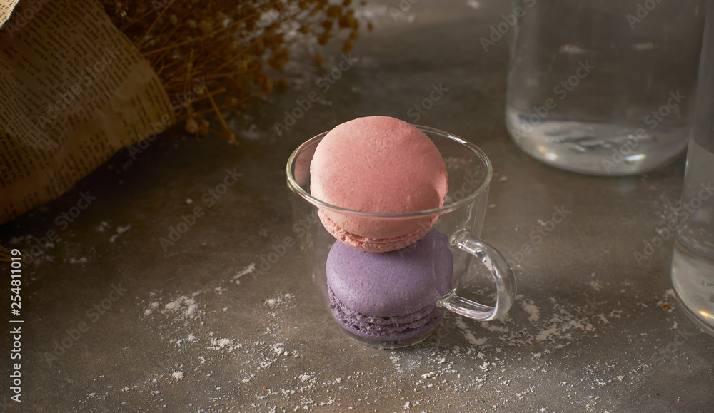 Pink and purple macarons on glass cup .