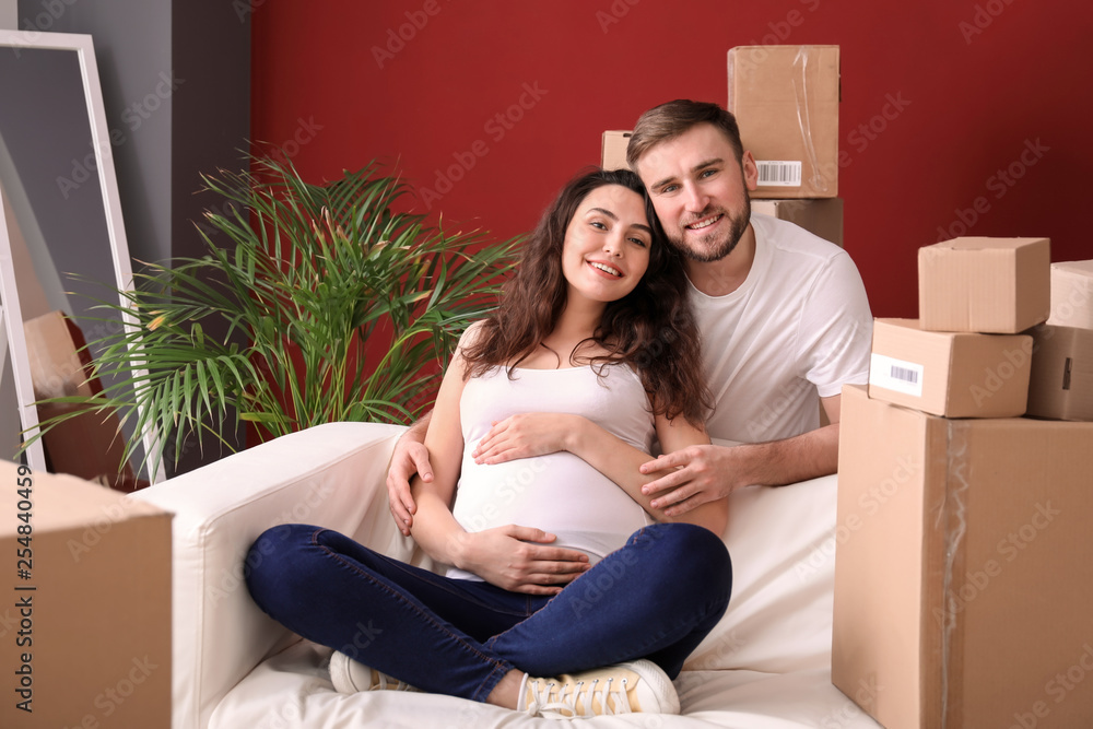 Happy pregnant couple with belongings at new home