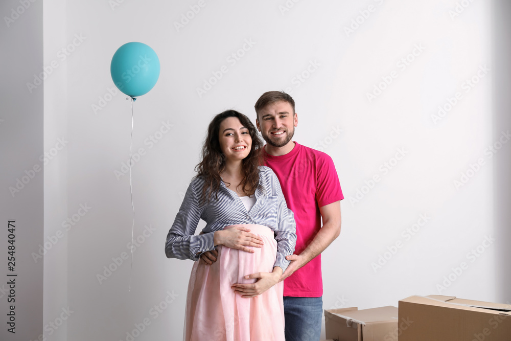 Happy pregnant couple with belongings at new home