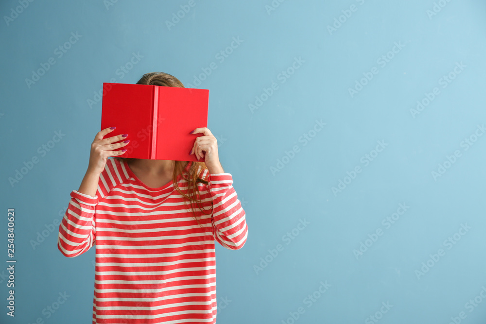 Schoolgirl with book on color background