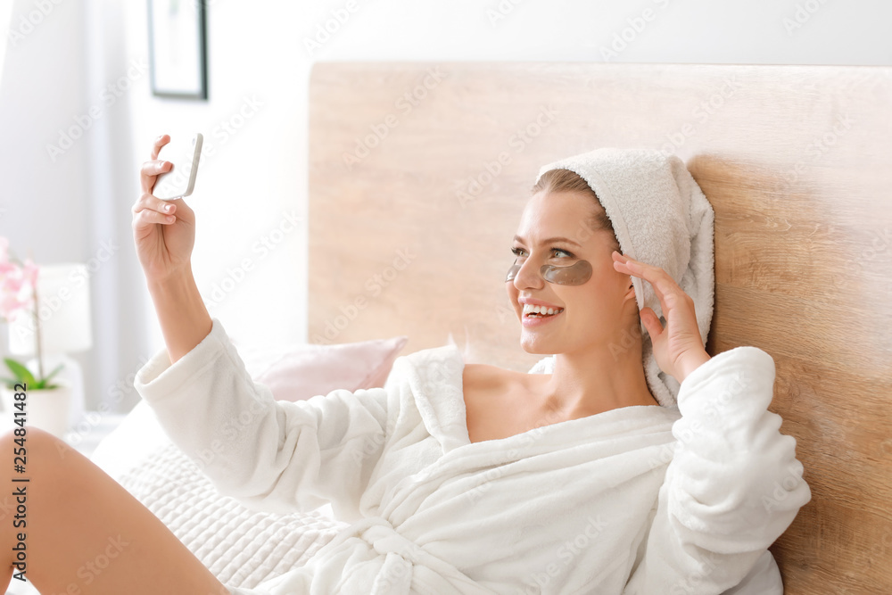 Young woman with under-eye patches taking selfie at home