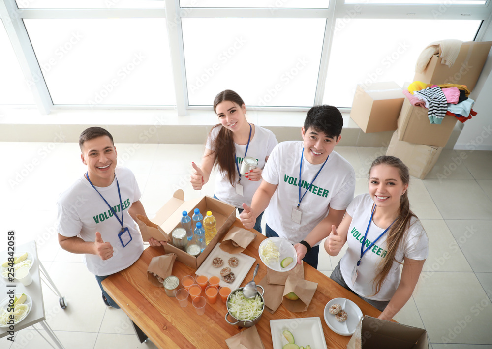 Young volunteers with food for poor people indoors