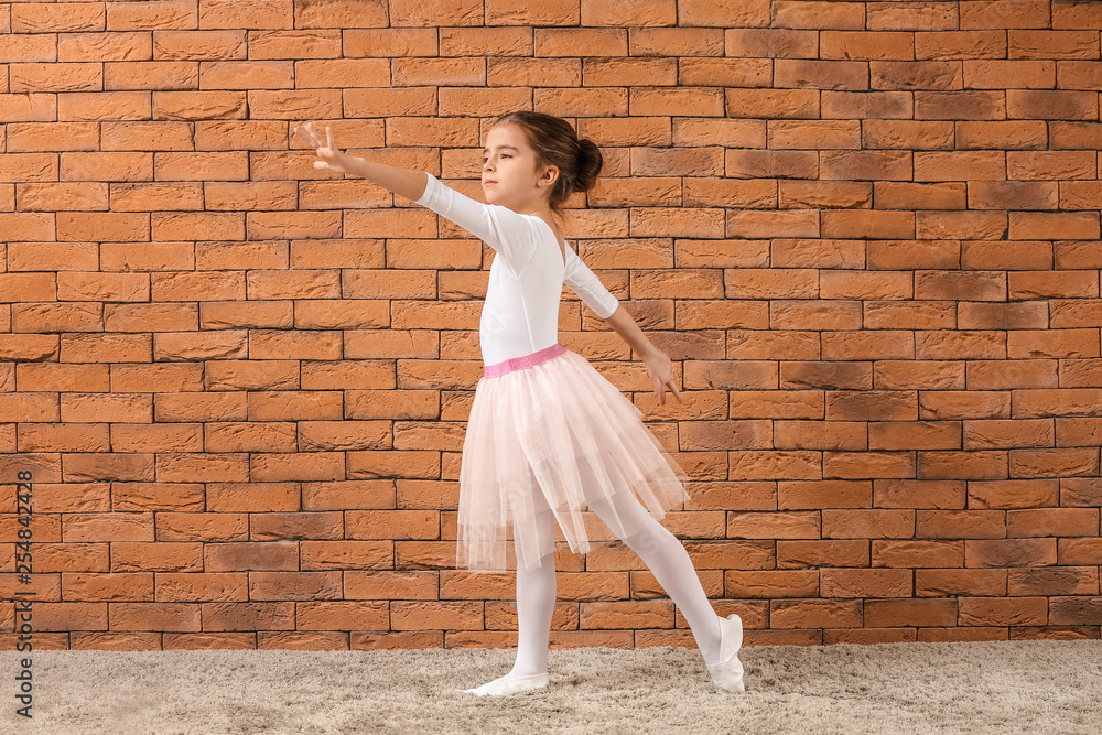 Cute little ballerina against brick wall