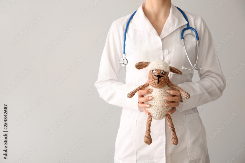 Pediatrician with toy on light background