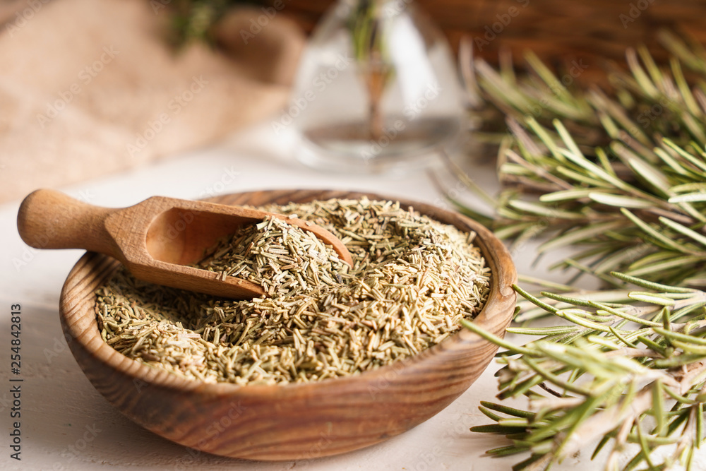 Bowl with dry rosemary and scoop on table