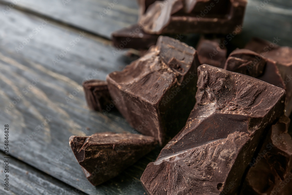 Pieces of tasty dark chocolate on wooden background