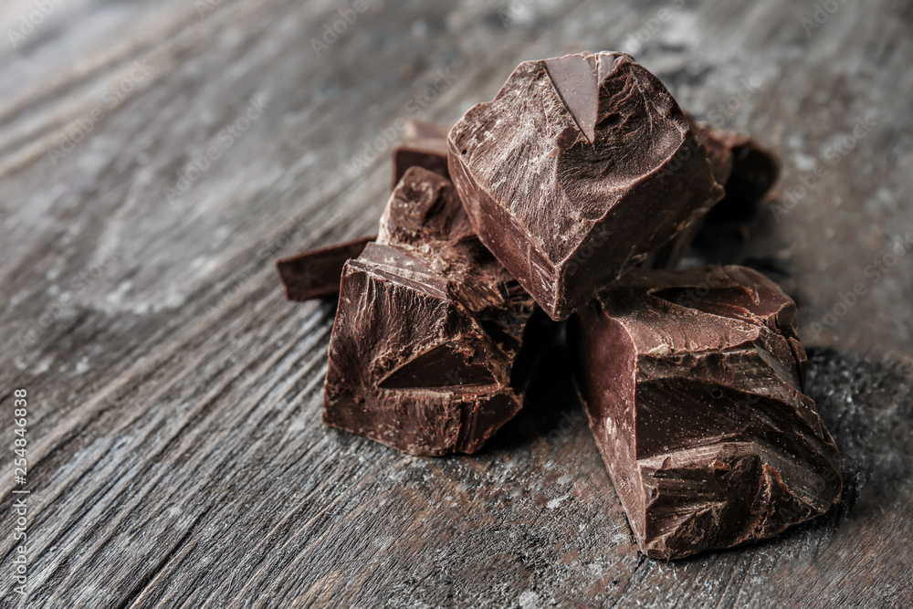 Pieces of tasty dark chocolate on wooden background