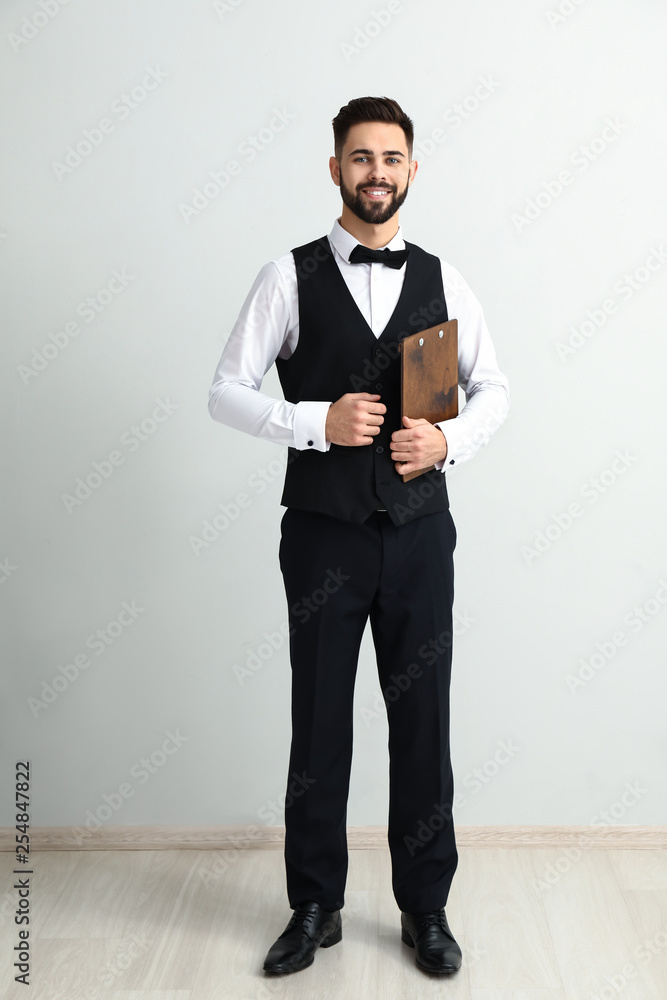 Waiter with menu near light wall