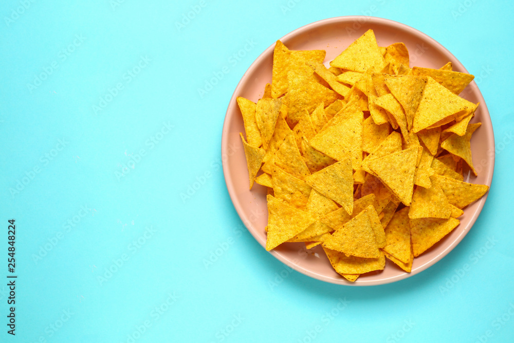 Plate with tasty nachos on color background