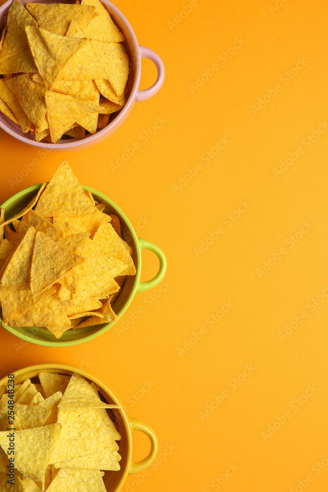 Pots with tasty nachos on color background