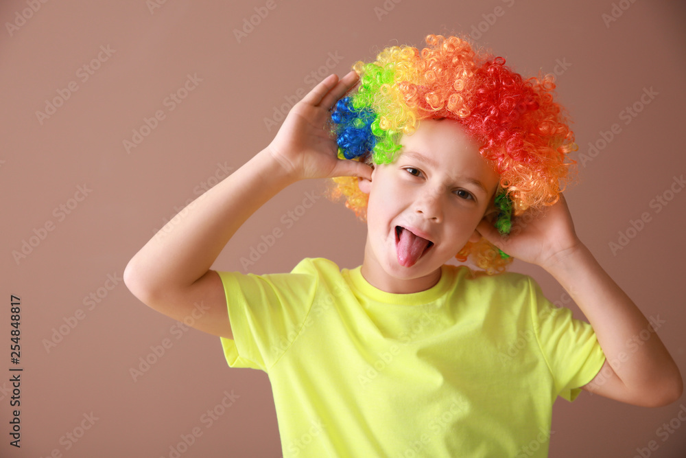 Little boy in funny disguise on color background. April fools day celebration