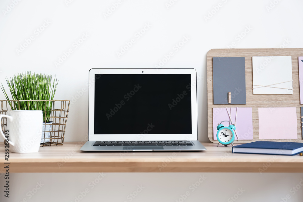 Laptop and alarm clock on table