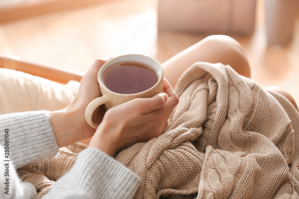 Young woman drinking hot tea at home, closeup