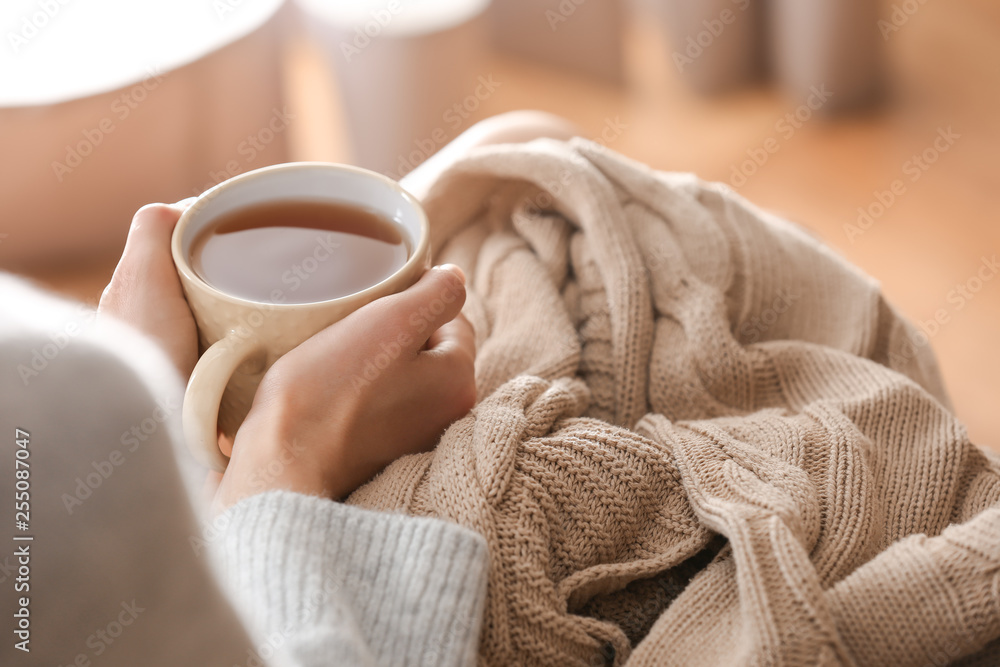 Young woman drinking hot tea at home, closeup