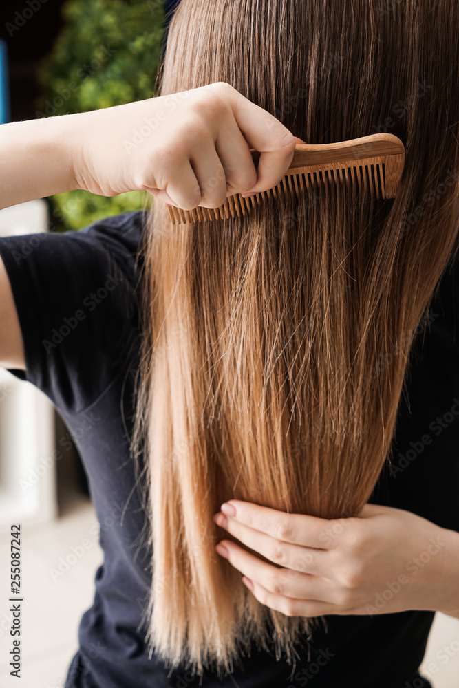 Young woman combing her long hair