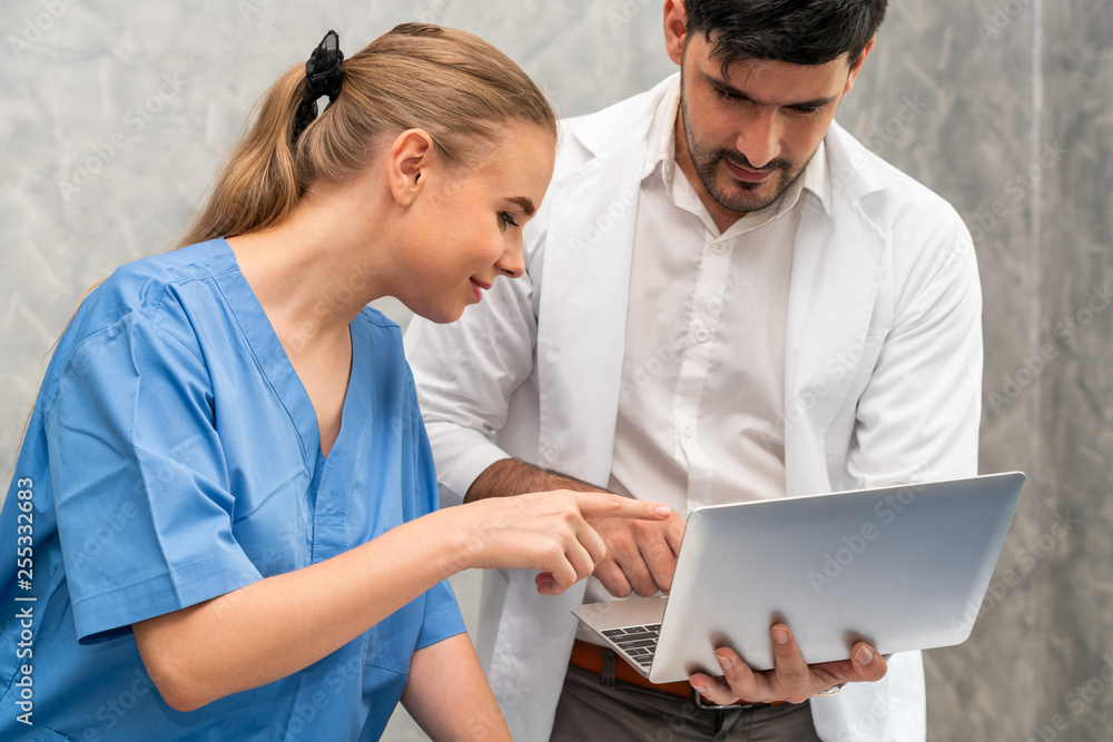 Happy doctor and nurse working with laptop computer in hospital office. Healthcare and medical conce