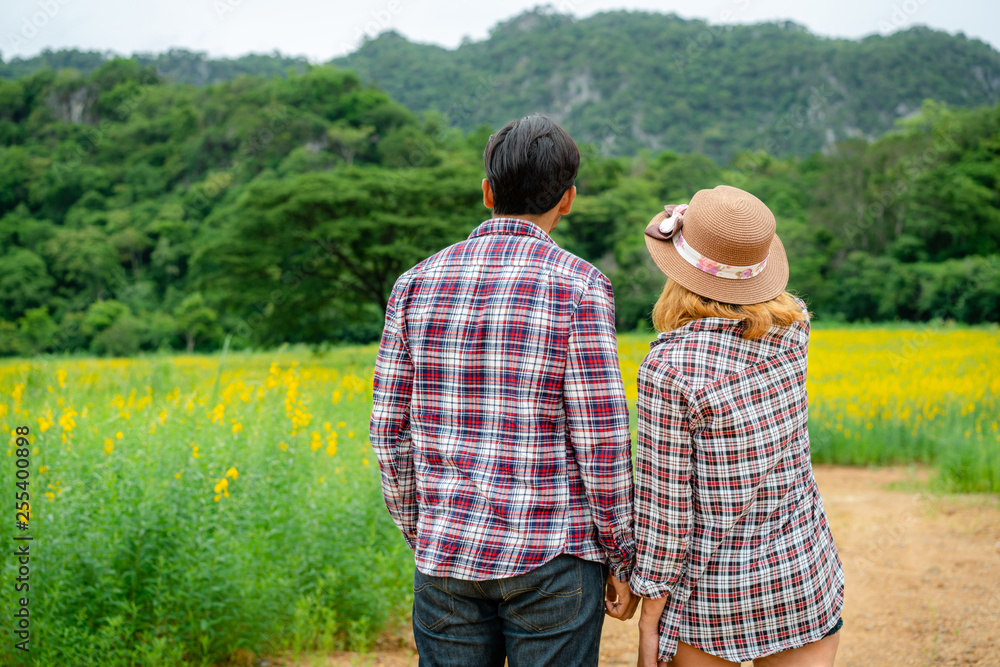 Happy couple take a romantic walk in green grass field on the hills. Travel and honeymoon concept.