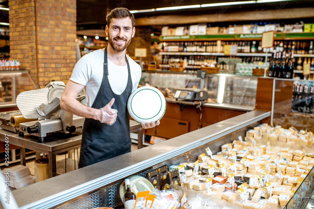 Portrait of a cheese seller in uniform standing with cheese head in the supermarket