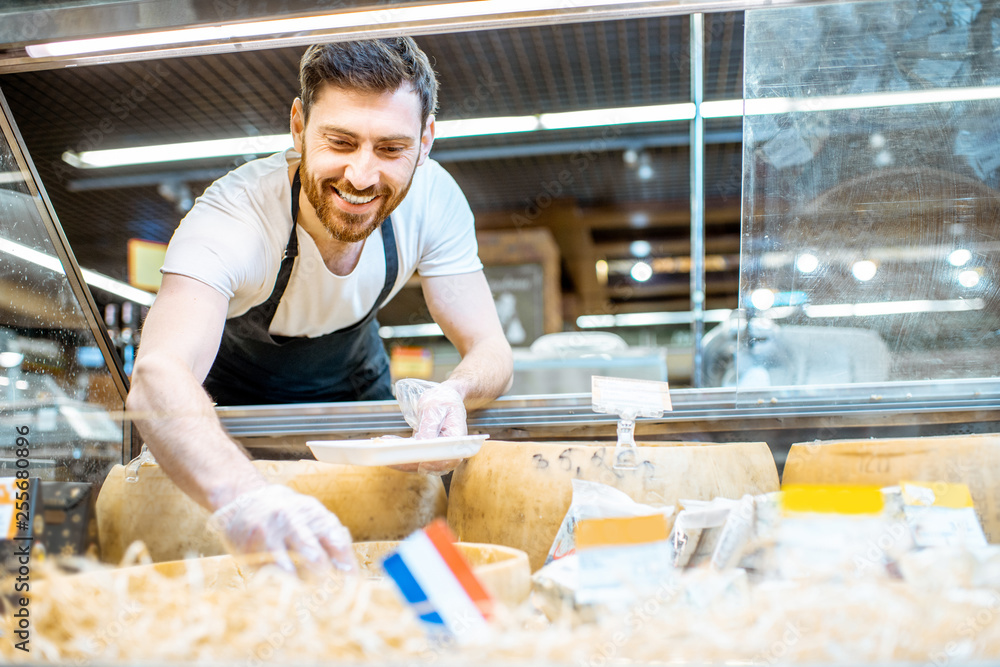 Portrait of a shop worker packing parmesan into the trail, selling cheese in the supermarket