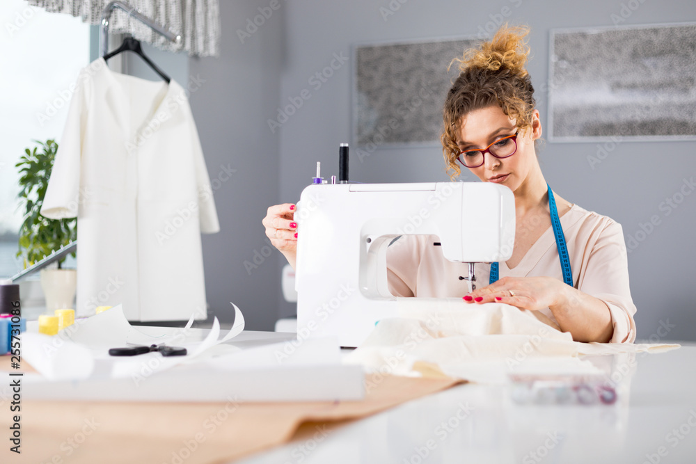 Tailor during work using sewing machine, fashion designer at workshop