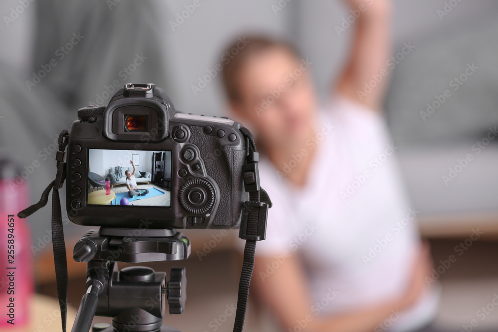 Young female blogger recording sports video at home