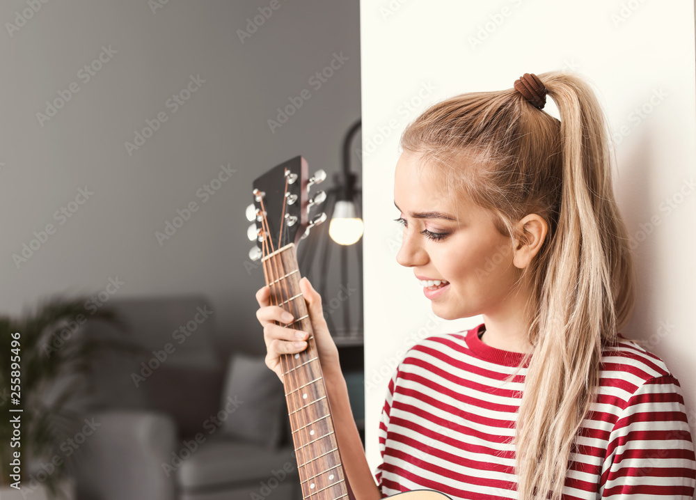 Beautiful young woman playing guitar at home