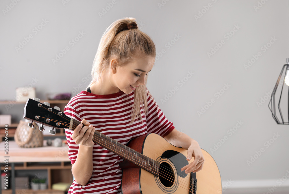 美丽的年轻女子在家弹吉他