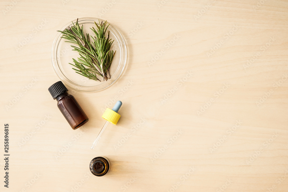 Bottles of oil and fresh rosemary on wooden table