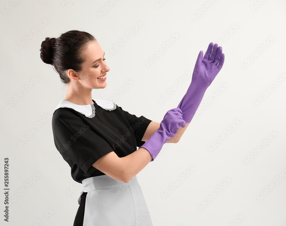 Portrait of beautiful female housekeeper wearing gloves on white background