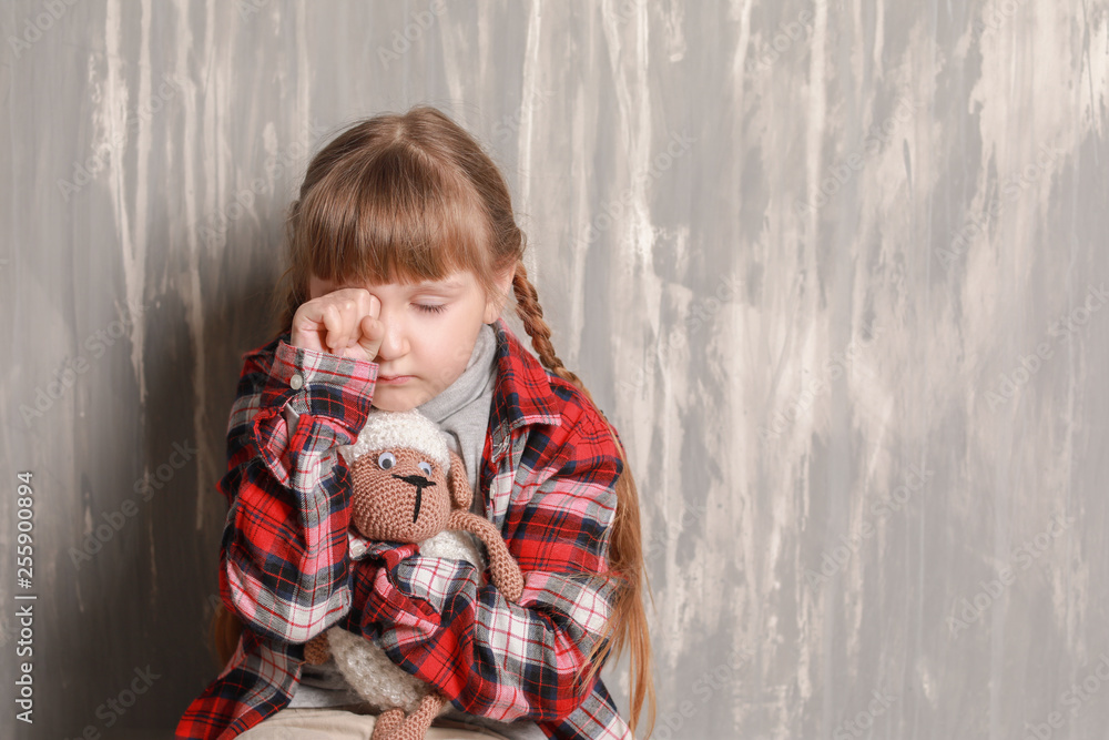 Portrait of sad little girl on grey background