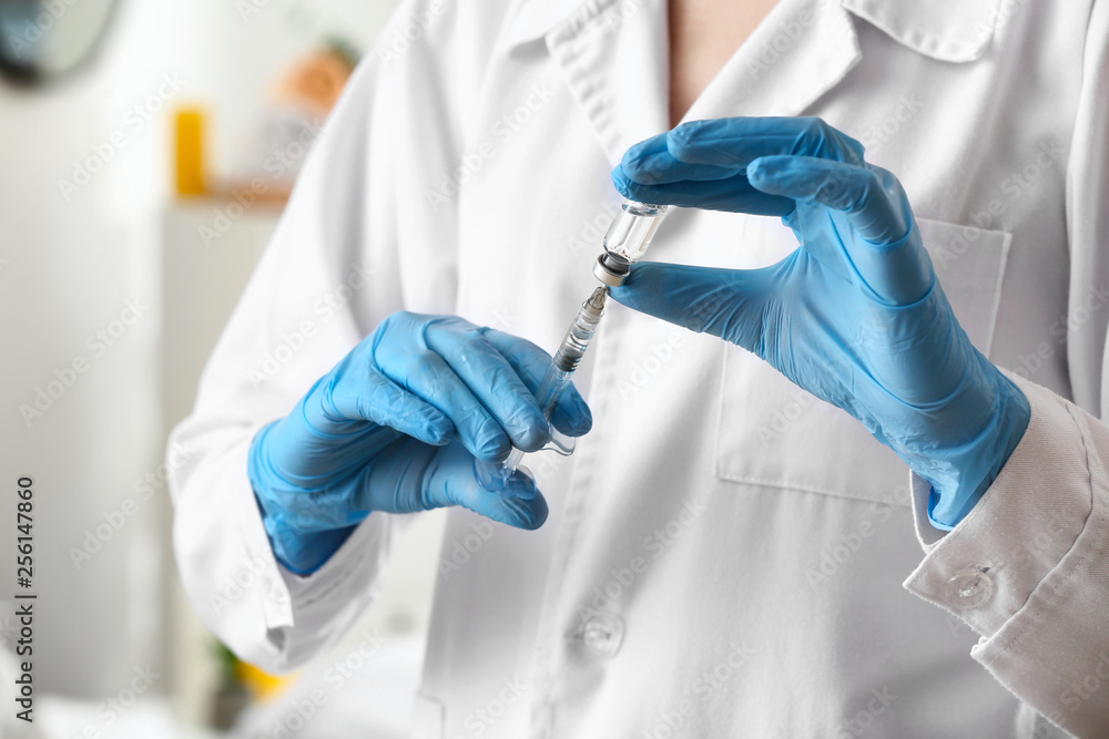 Cosmetologist holding syringe with filler and ampule, closeup