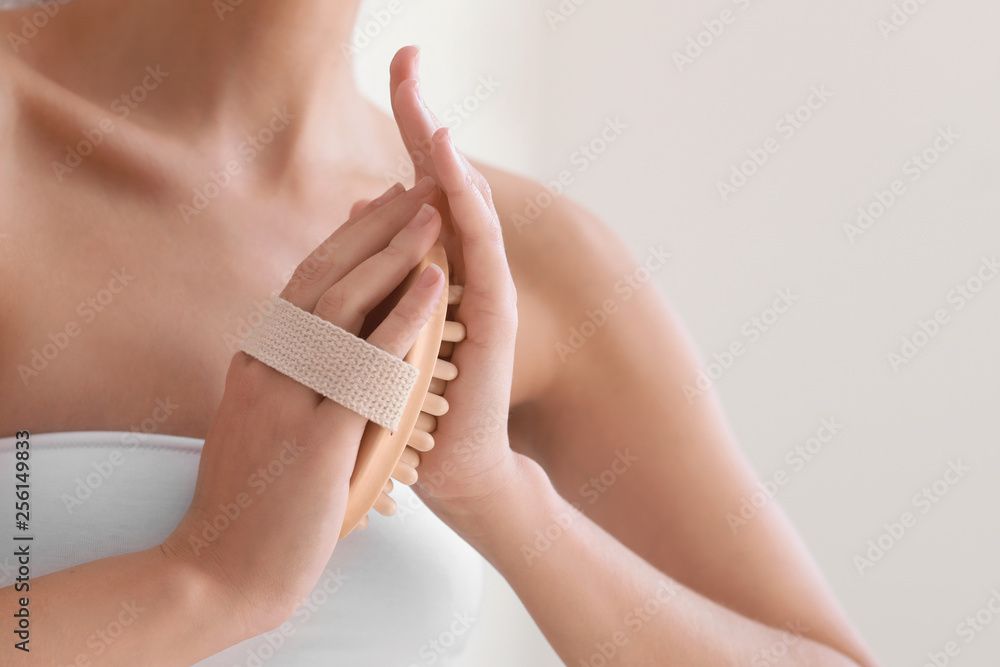 Beautiful young woman with massage brush in bathroom, closeup