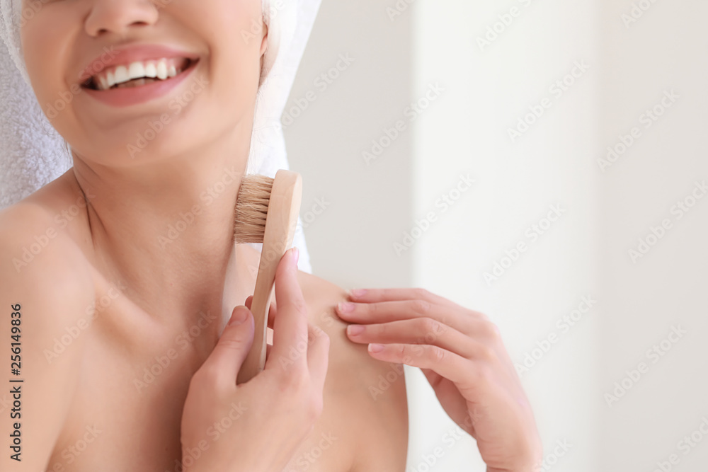 Beautiful young woman with massage brush in bathroom, closeup