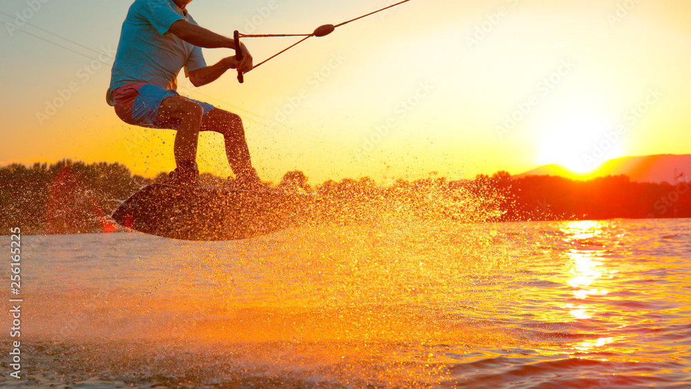 CLOSE UP: Cool wakeboarder does a 180 ollie while speeding across the lake.